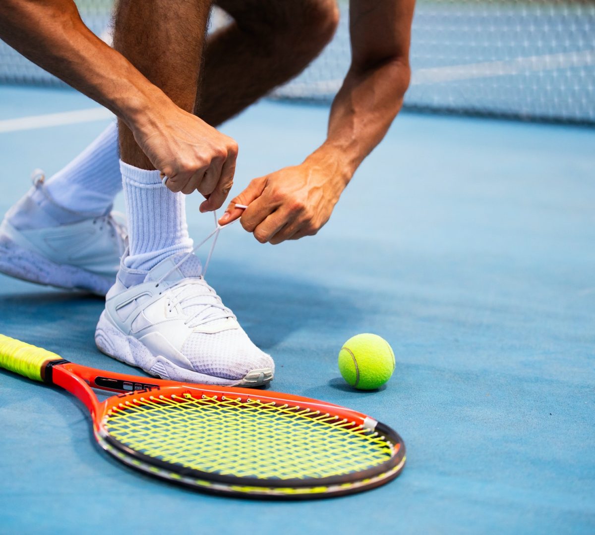Tennis athlete player getting ready tying shoe laces during game on outdoor